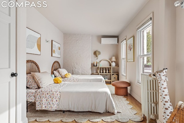 bedroom featuring wood-type flooring, radiator heating unit, and a wall unit AC