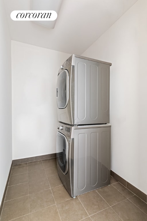 clothes washing area featuring tile patterned floors and stacked washer / dryer