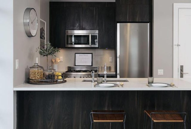 kitchen featuring appliances with stainless steel finishes, light countertops, a sink, and a peninsula