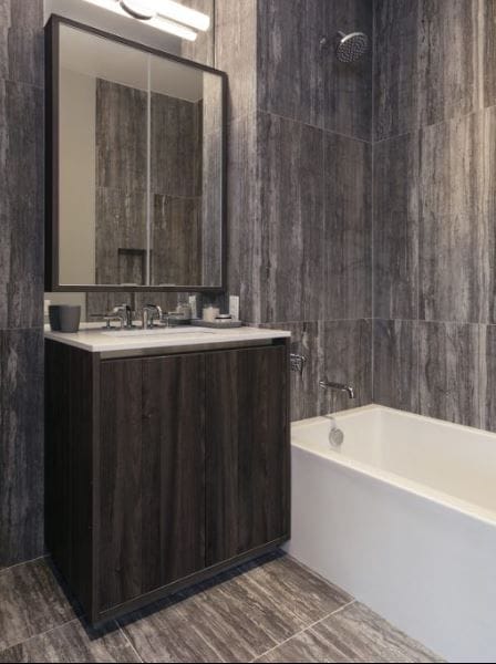 bathroom featuring shower / bathtub combination, vanity, and tile walls