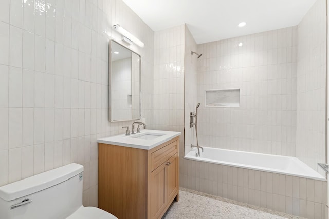 full bath featuring tile walls, tiled shower / bath, toilet, and vanity