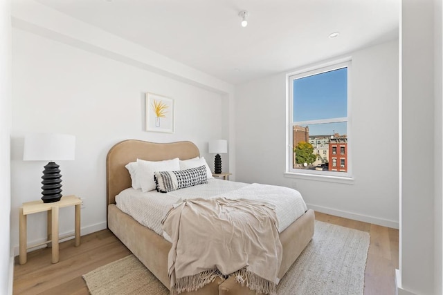 bedroom featuring light wood finished floors and baseboards