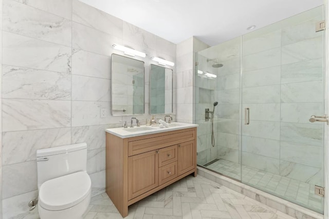 bathroom featuring a shower with shower door, vanity, tile walls, and toilet