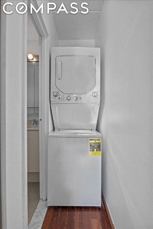 washroom with stacked washer and dryer, dark hardwood / wood-style floors, sink, and a textured ceiling