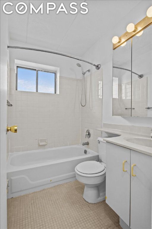 full bathroom with tiled shower / bath, tile patterned floors, toilet, and vanity