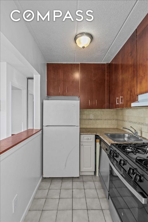 kitchen featuring sink, gas stove, decorative backsplash, stainless steel dishwasher, and white fridge