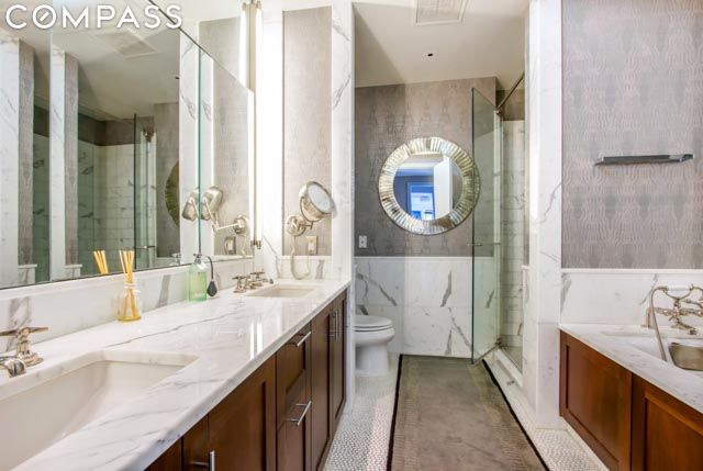 bathroom with walk in shower, vanity, toilet, and tile walls