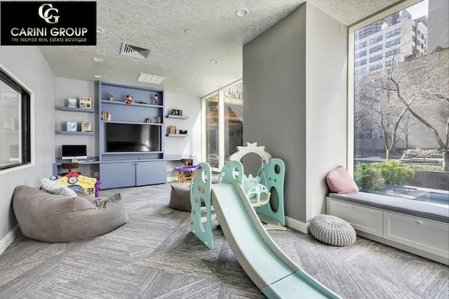 game room with visible vents, a textured ceiling, baseboards, and carpet floors