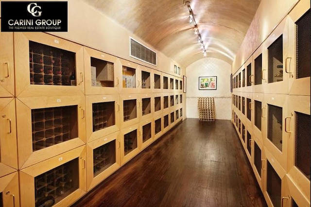 wine room with visible vents, wood-type flooring, and vaulted ceiling