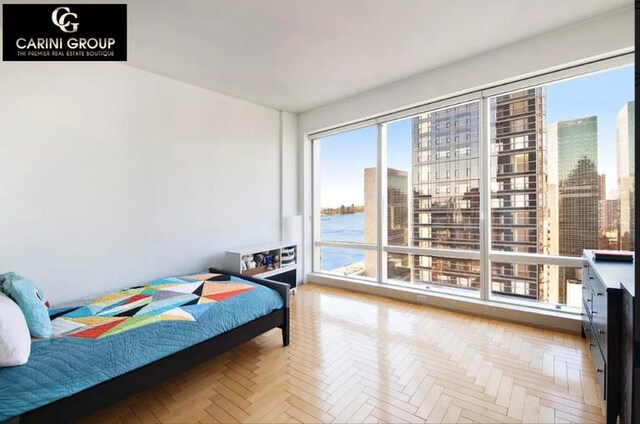 bedroom featuring light parquet flooring and a water view