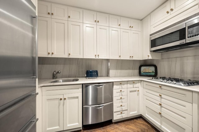 kitchen featuring sink, decorative backsplash, stainless steel appliances, and white cabinets