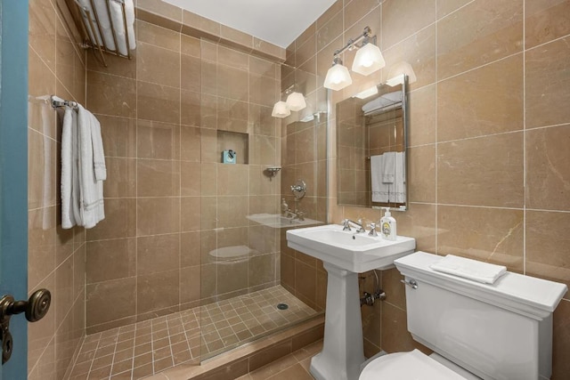 bathroom featuring tile walls, sink, toilet, and a tile shower