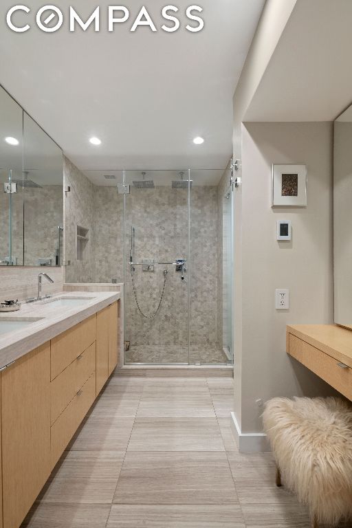 bathroom with a shower with shower door, vanity, and tile patterned flooring