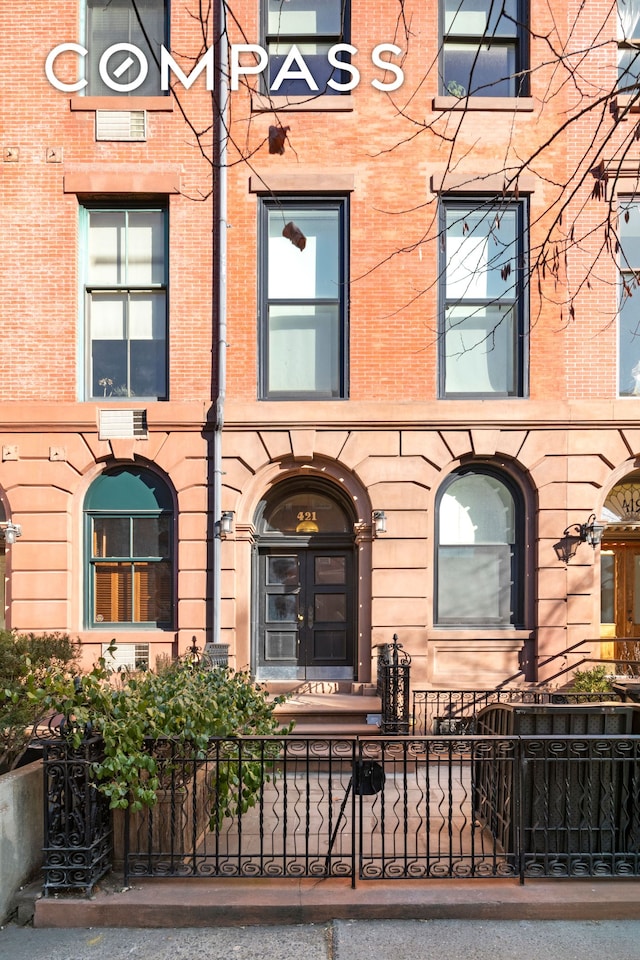 doorway to property featuring brick siding and fence