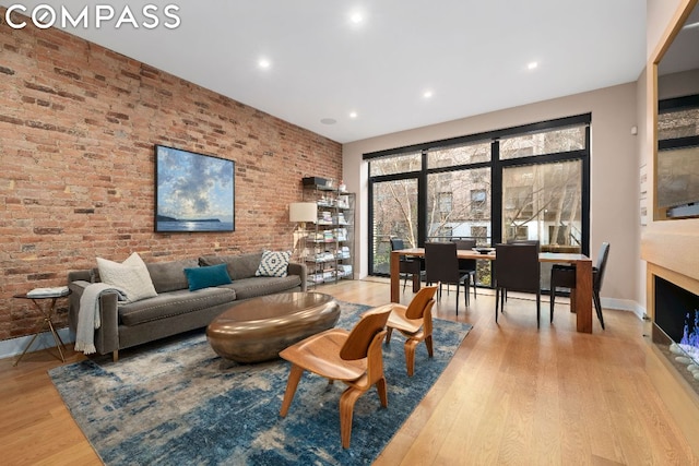 living room featuring brick wall and light hardwood / wood-style flooring