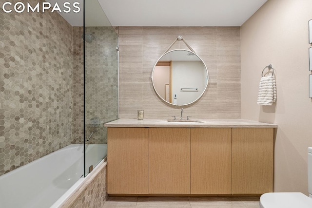 full bathroom featuring toilet, tile patterned floors, tiled shower / bath, and vanity