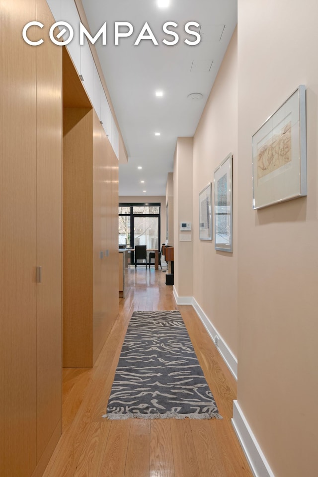 corridor featuring light wood-style flooring, baseboards, and recessed lighting