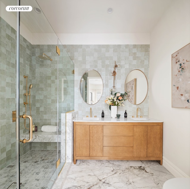 bathroom with marble finish floor, double vanity, a sink, and a shower stall