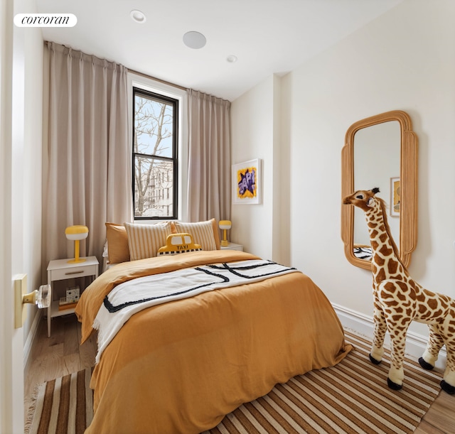 bedroom with visible vents, baseboards, and wood finished floors