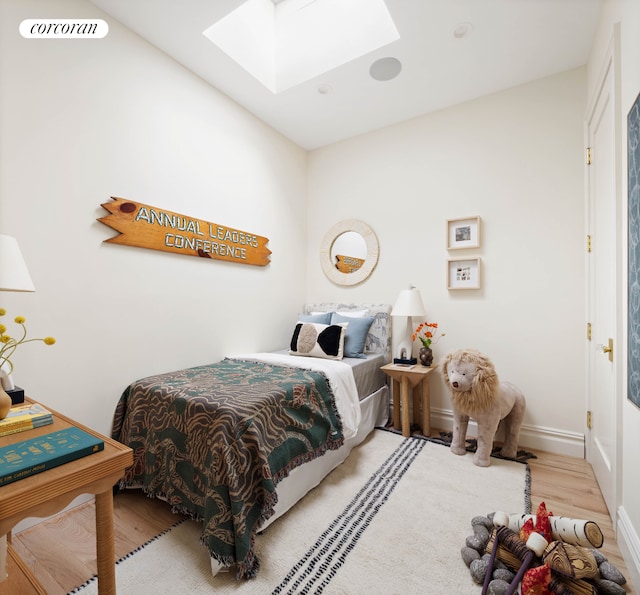 bedroom with a skylight, wood finished floors, visible vents, and baseboards