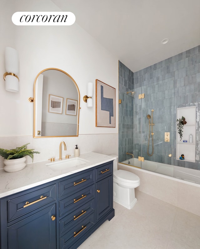 full bath with tile patterned flooring, tiled shower / bath, toilet, and vanity