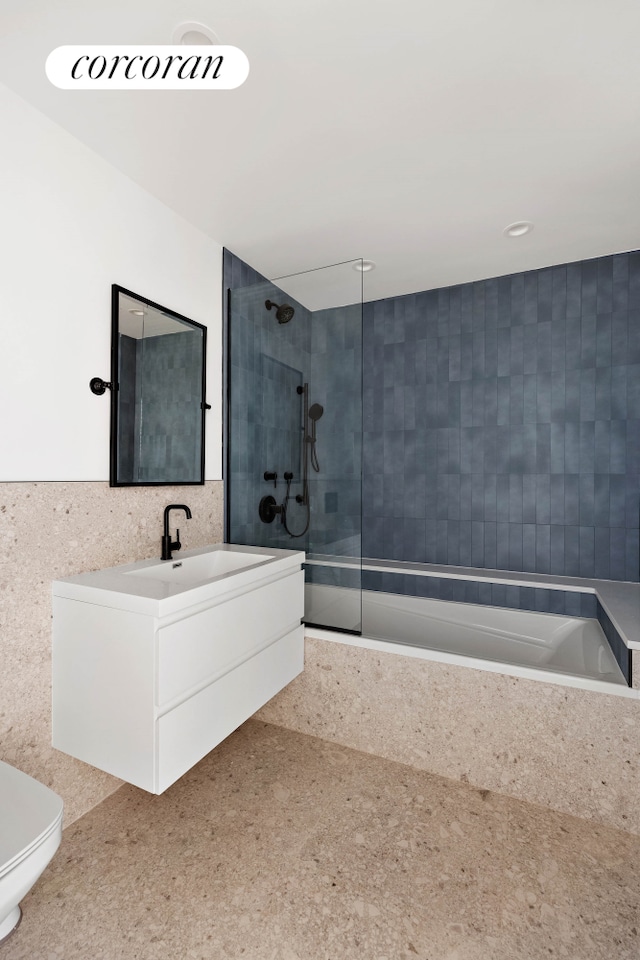 bathroom featuring toilet, a wainscoted wall, tub / shower combination, vanity, and tile walls