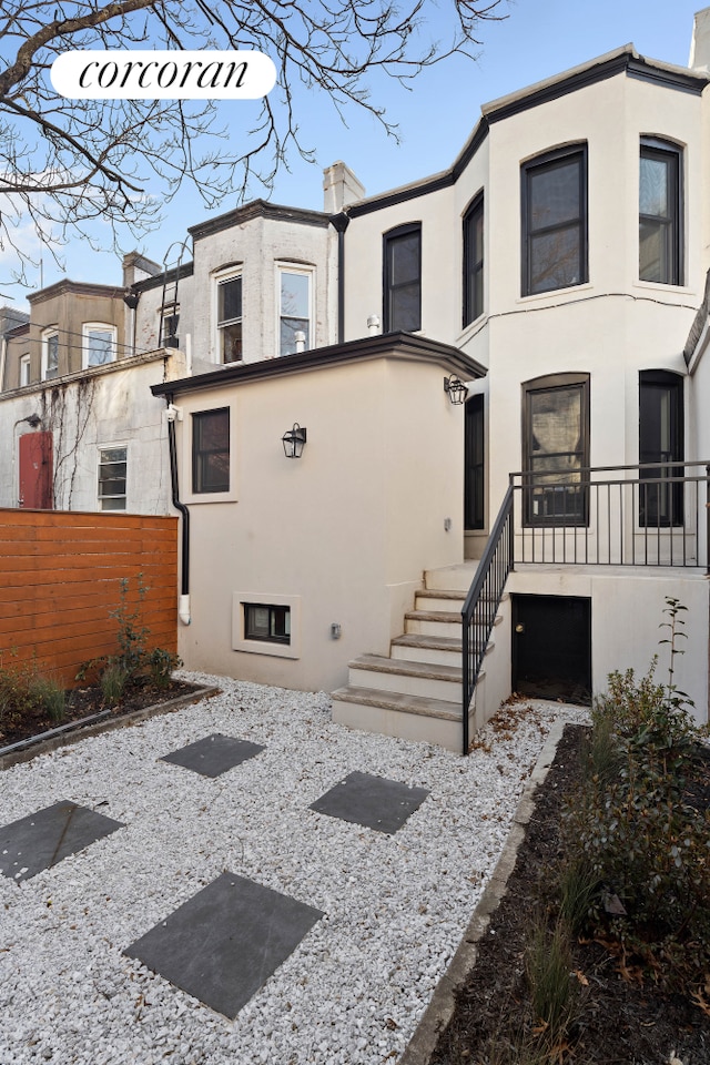 view of front facade with fence and stucco siding