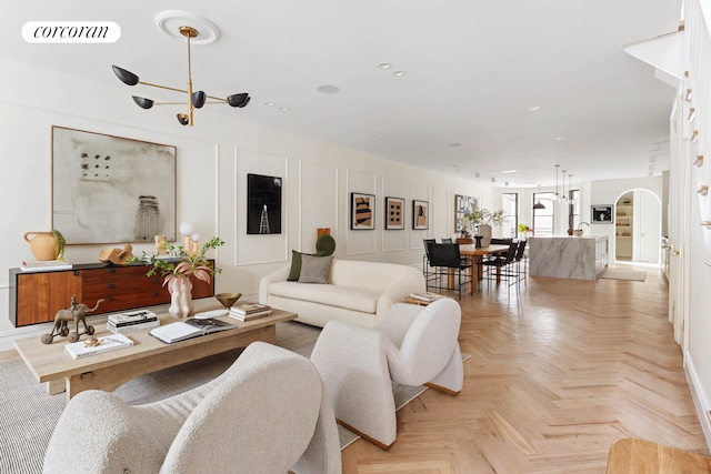 living room featuring arched walkways, a notable chandelier, recessed lighting, visible vents, and a decorative wall