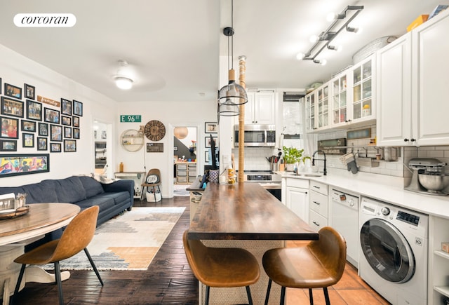 kitchen with washer / clothes dryer, white cabinetry, decorative light fixtures, and stainless steel appliances