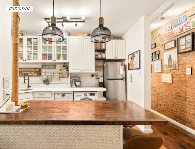 kitchen with white cabinets, washer / dryer, sink, stainless steel refrigerator, and butcher block countertops