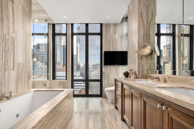 bathroom with tile walls, toilet, a garden tub, and double vanity