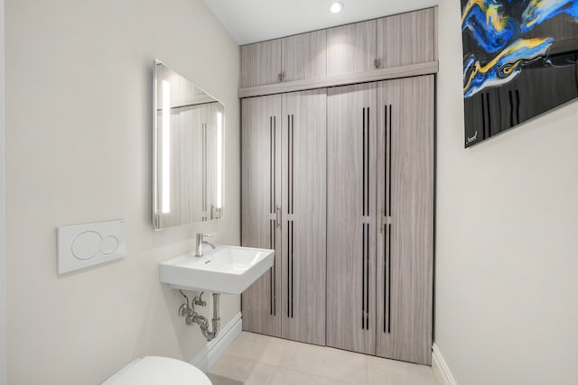 bathroom featuring tile patterned flooring, toilet, and baseboards