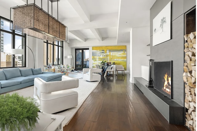 living room featuring dark wood finished floors, beam ceiling, a warm lit fireplace, and a high ceiling