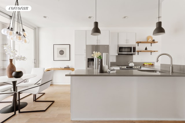 kitchen with pendant lighting, stainless steel appliances, sink, and white cabinets