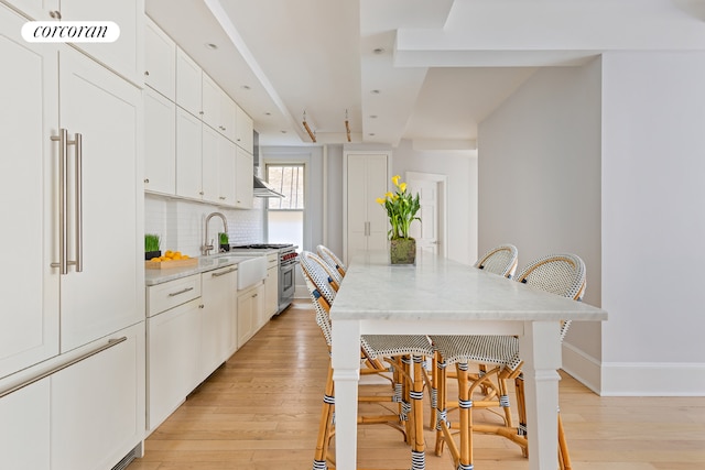 kitchen with light stone counters, white cabinetry, a breakfast bar area, and high quality appliances