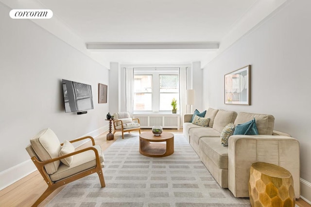 living room featuring beamed ceiling, radiator heating unit, and light hardwood / wood-style flooring