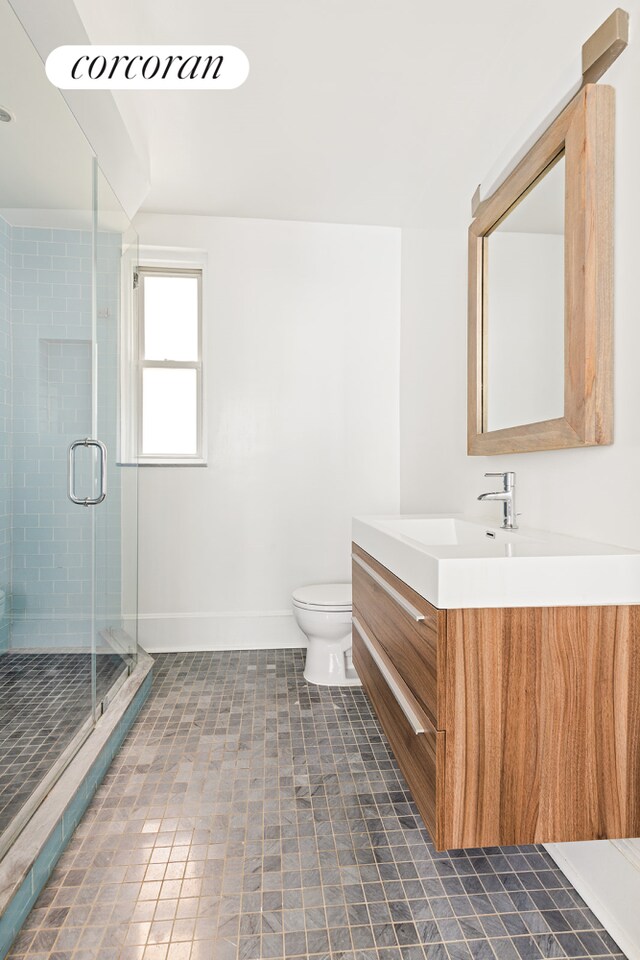 bathroom featuring tile patterned floors, vanity, toilet, and a shower with door