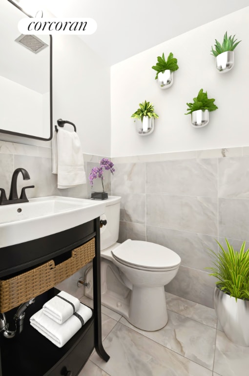 bathroom with tile walls, vanity, and toilet