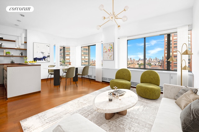 living area featuring a baseboard radiator, wood finished floors, visible vents, a view of city, and an inviting chandelier