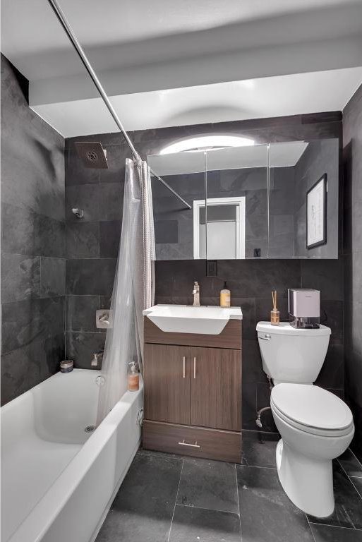 full bathroom with toilet, tile walls, vanity, and shower / tub combo