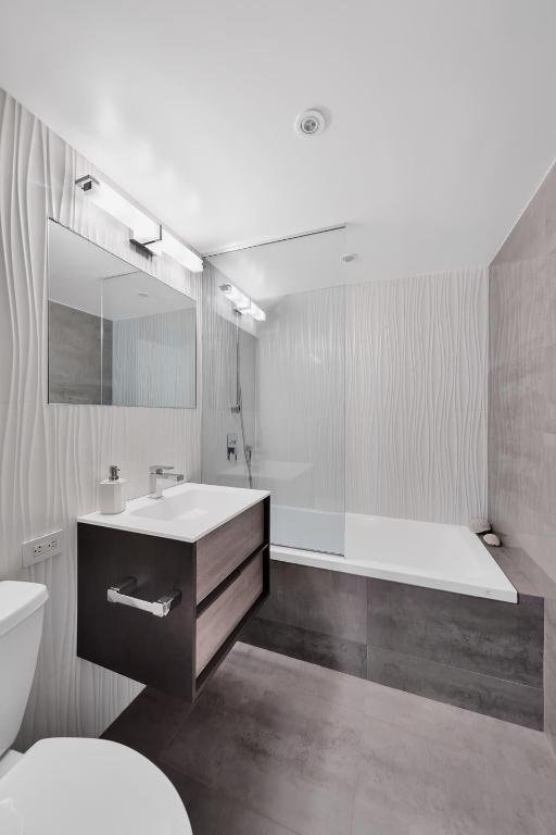 full bathroom featuring vanity, tiled shower / bath combo, tile walls, and toilet