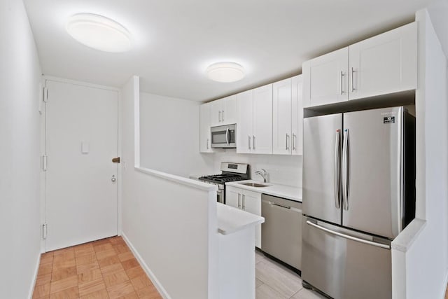 kitchen featuring appliances with stainless steel finishes, sink, light parquet floors, and white cabinets