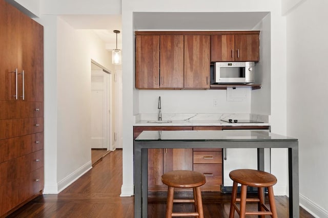 kitchen featuring pendant lighting, sink, a kitchen breakfast bar, and black electric stovetop