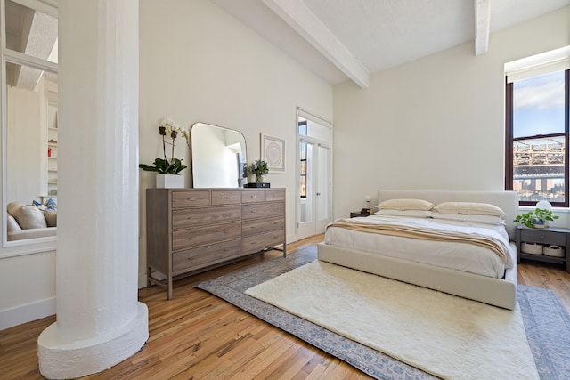 bedroom featuring wood-type flooring and beamed ceiling