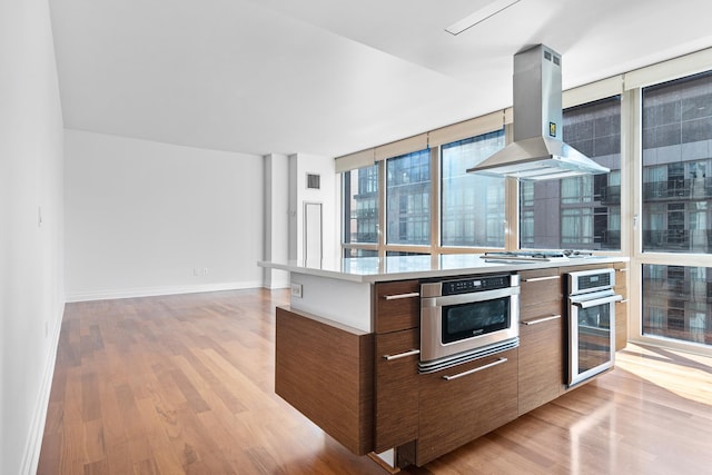 kitchen featuring island exhaust hood, light wood-type flooring, oven, and modern cabinets