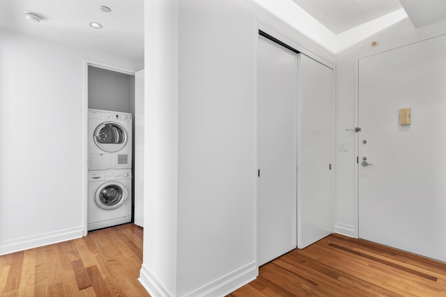 laundry room with laundry area, stacked washer / dryer, and light wood-style floors