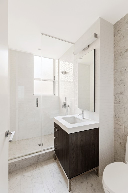 bathroom with vanity, toilet, an enclosed shower, and tile walls