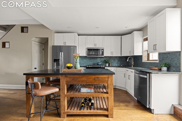 kitchen with sink, white cabinetry, stainless steel appliances, light hardwood / wood-style floors, and decorative backsplash