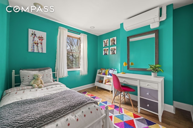 bedroom with baseboards, an AC wall unit, and wood finished floors