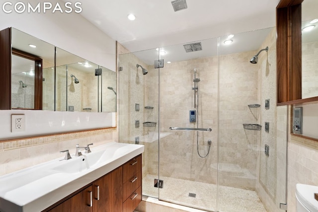 bathroom with an enclosed shower, vanity, tile walls, and tasteful backsplash